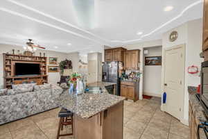 Kitchen featuring light tile patterned floors, sink, stainless steel appliances, a spacious island, and a breakfast bar area