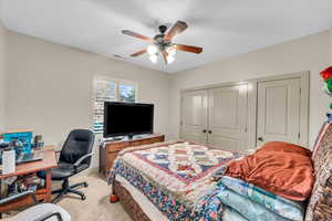 Carpeted bedroom with a closet and ceiling fan