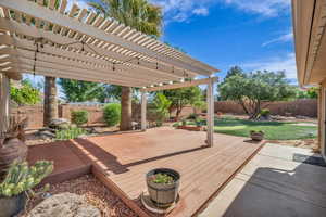 Wooden terrace with a lawn, a pergola, and a fenced backyard