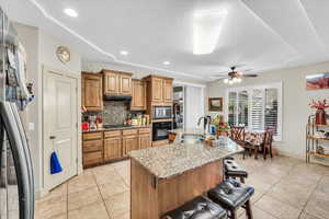 Kitchen with a kitchen island with sink, a breakfast bar, sink, appliances with stainless steel finishes, and light tile patterned flooring