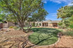 Back of house featuring stucco siding, a yard, a gate, a patio, and a pergola
