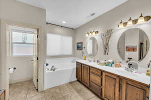 Bathroom with a bathing tub, vanity, and tile patterned flooring