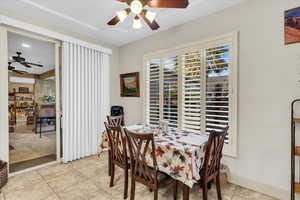 Tiled dining area with an AC wall unit and ceiling fan