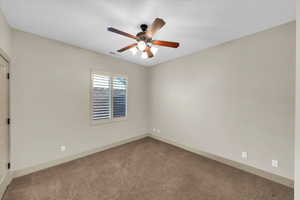 Carpeted spare room featuring ceiling fan