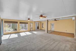 Unfurnished living room with ceiling fan, carpet floors, and a wall mounted AC