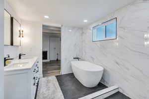 Bathroom featuring tile walls, vanity, and a tub