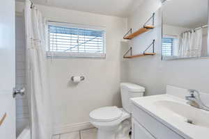 Full bathroom with vanity, shower / bath combo with shower curtain, tile patterned flooring, and toilet