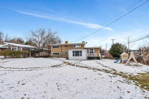 Snow covered property with a playground