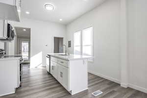 Kitchen featuring an island with sink, stainless steel appliances, a wealth of natural light, sink, and white cabinetry