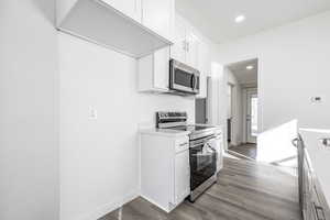 Kitchen featuring hardwood / wood-style flooring, white cabinets, and stainless steel appliances