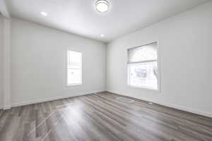 Empty room with a healthy amount of sunlight and hardwood / wood-style flooring