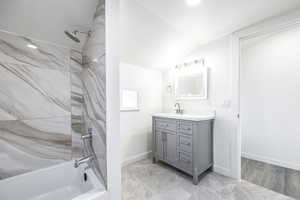 Bathroom featuring tiled shower / bath combo, vaulted ceiling, and vanity