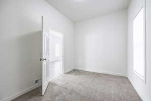 Empty room with a healthy amount of sunlight and carpet floors