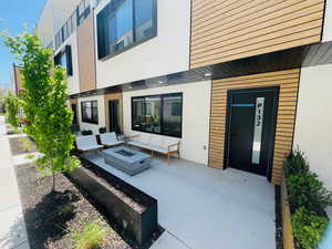 Rear view of house with an outdoor fire pit, a patio area, and stucco siding