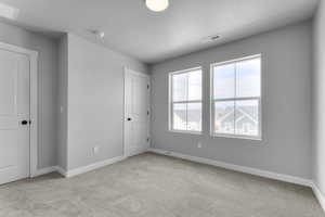 Unfurnished bedroom with light carpet, baseboards, and a textured ceiling