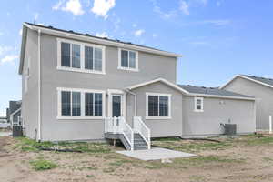 Rear view of property with stucco siding and central AC