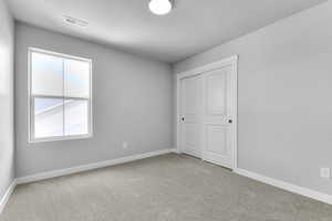 Unfurnished bedroom featuring carpet, baseboards, a textured ceiling, and a closet