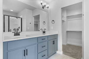 Full bath featuring double vanity, a spacious closet, and baseboards