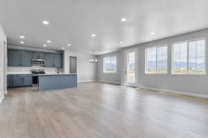 Kitchen featuring appliances with stainless steel finishes, a sink, open floor plan, light countertops, and recessed lighting