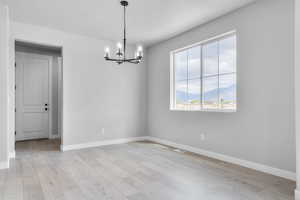 Spare room with a chandelier, baseboards, light wood-style flooring, and a mountain view