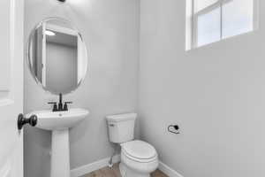 Bathroom featuring toilet, wood finished floors, and baseboards