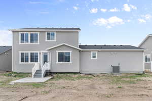 Back of house with stucco siding and central AC unit