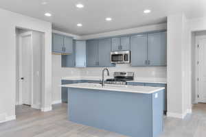 Kitchen with appliances with stainless steel finishes, light wood-type flooring, light countertops, baseboards, and recessed lighting