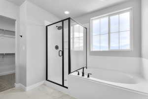 Full bath featuring a shower stall, plenty of natural light, a spacious closet, a bath, and recessed lighting