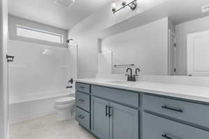 Full bathroom with toilet, vanity, shower / washtub combination, and marble look tiles