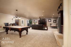 Playroom featuring rail lighting, pool table, light colored carpet, a textured ceiling, and ceiling fan