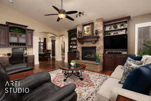 Living room featuring ornate columns, vaulted ceiling, a fireplace, ceiling fan, and dark wood-type flooring