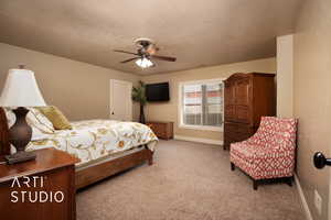 Bedroom with ceiling fan, carpet, and a textured ceiling