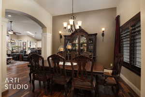 Dining space with lofted ceiling, dark wood-type flooring, and ceiling fan with notable chandelier