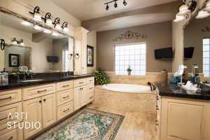 Master Bathroom with a relaxing tiled tub, vanity, plenty of natural light, and wood-type flooring