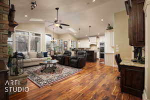 Living room featuring dark hardwood / wood-style floors, ceiling fan with notable chandelier, high vaulted ceiling, and a skylight