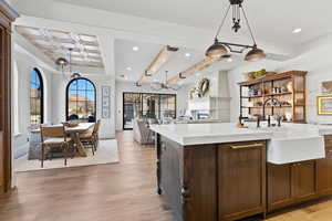 Kitchen featuring light wood-type flooring, a premium fireplace, pendant lighting, sink, and a kitchen island with sink