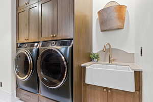 Laundry area with washing machine and dryer, sink, and cabinets