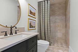 Bathroom with curtained shower, vanity, and toilet