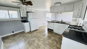 Kitchen featuring sink, white appliances, white cabinetry, and plenty of natural light