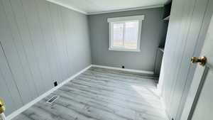 Laundry room with light hardwood / wood-style flooring and wooden walls