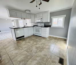 Kitchen with kitchen peninsula, sink, white appliances, ceiling fan, and light tile patterned floors