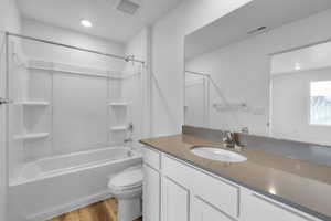 Full bathroom with hardwood / wood-style flooring, vanity, bathing tub / shower combination, and toilet