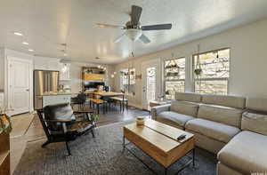 Living room featuring ceiling fan, wood-type flooring, and a textured ceiling