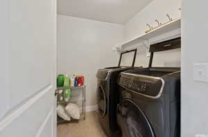 Laundry room with independent washer and dryer and light tile patterned floors