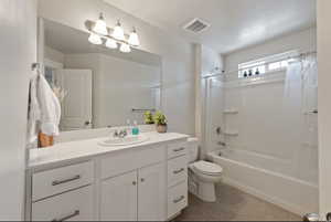 Full bathroom featuring toilet, tile patterned floors, shower / tub combo with curtain, and vanity