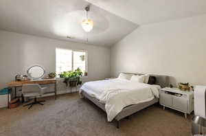 Carpeted bedroom featuring ceiling fan and lofted ceiling