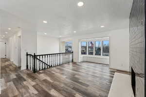 Empty room with a tile fireplace, hardwood / wood-style flooring, and a textured ceiling