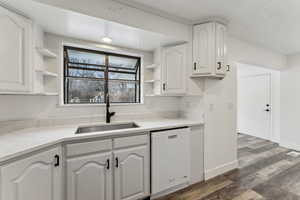 Kitchen with white cabinets, dishwasher, dark hardwood / wood-style flooring, and sink