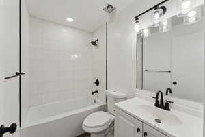 Full bathroom featuring vanity, tiled shower / bath, and toilet