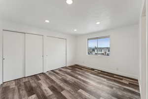 Unfurnished bedroom featuring two closets and dark wood-type flooring